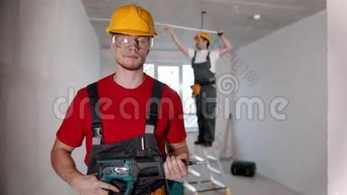<strong>选秀</strong>室的公寓维修-一名男子工人站在摄像机前，把钻头递给另一名男子